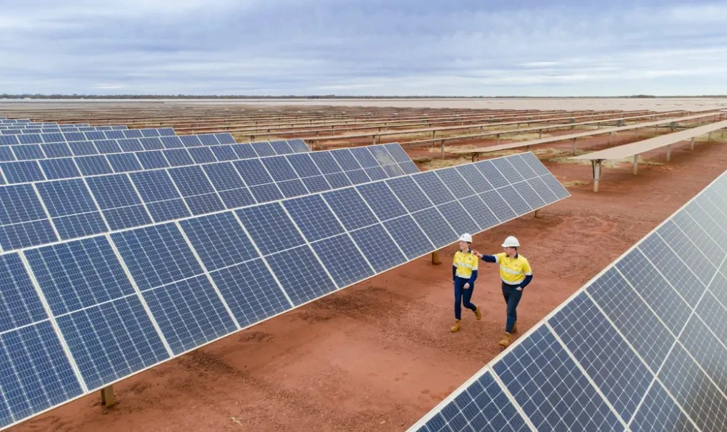 two people standing in front of solar panels
